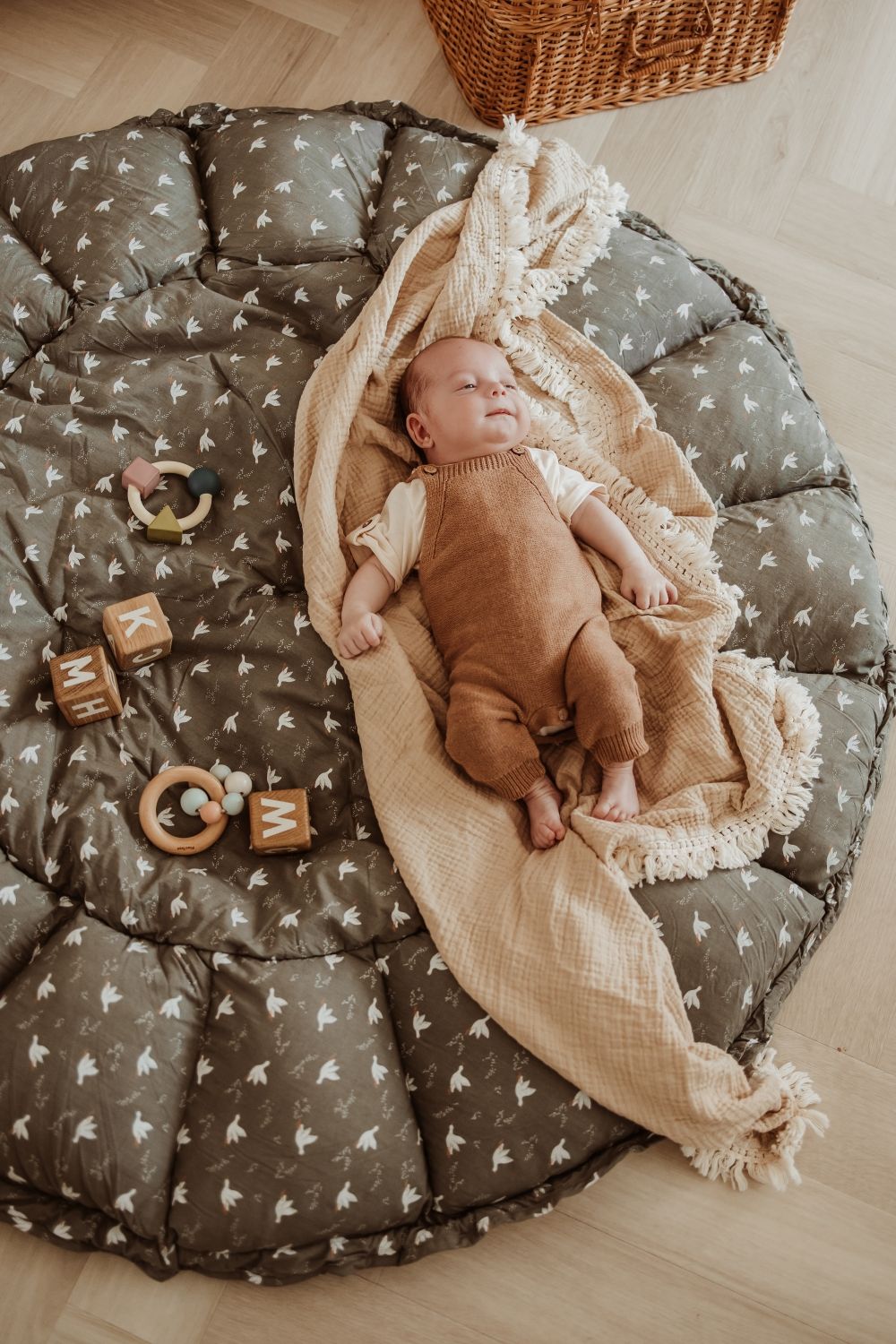 bloom birds babymat, open on floor, baby is lying on a blanket on the mat, wooden toys