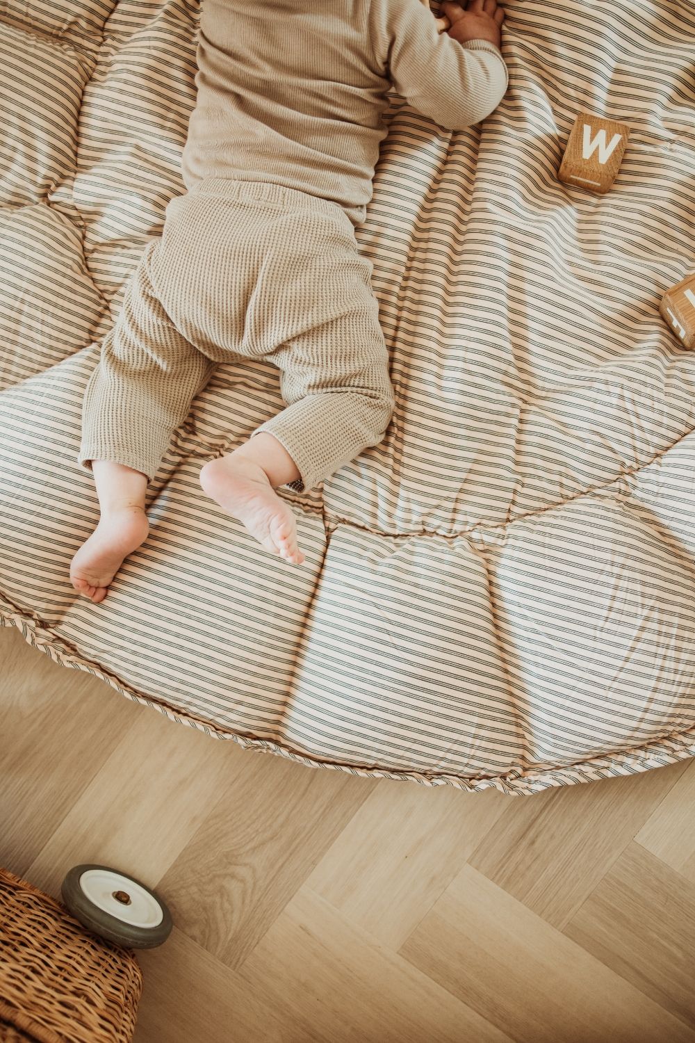 bloom stripes blue babymat, open on floor, baby is lying on the mat, wooden blocks