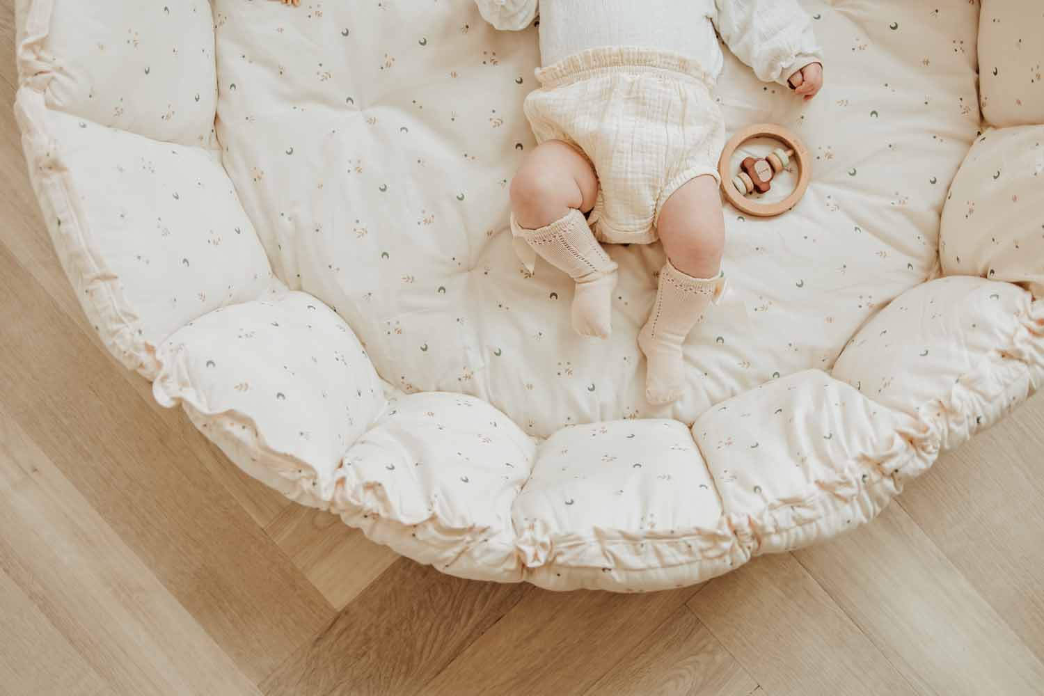 Bloom moon organic babymat, baby lying in crib with raised adges