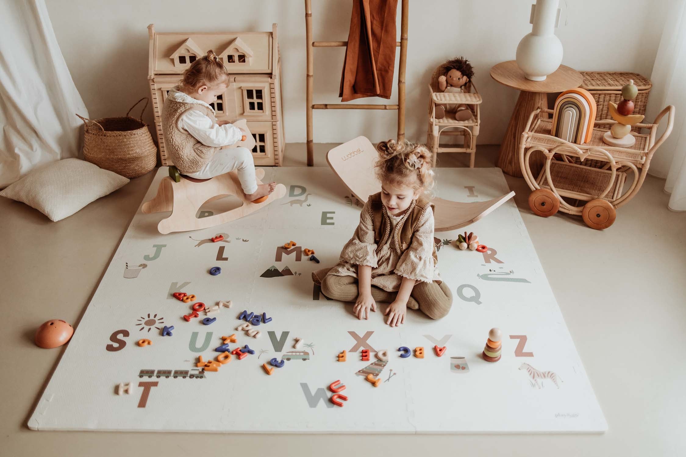 two kids sitting and playing at a puzzle mat.