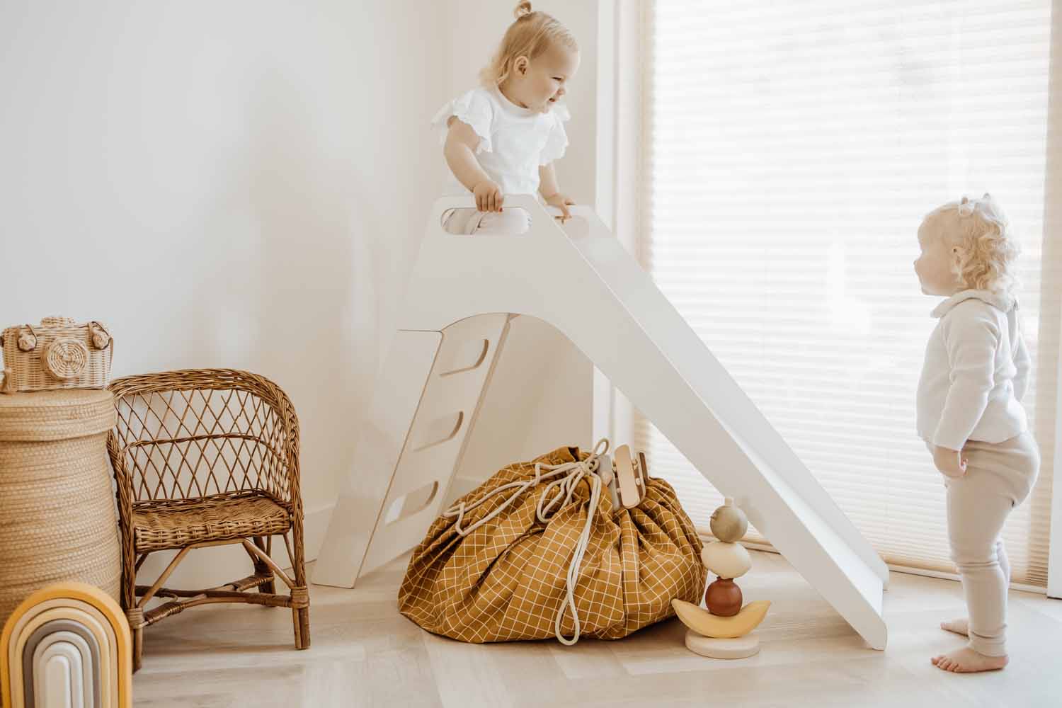 closed organic grid mustard storage bag, on floor in kidsroom, under white slide, children playing, wicker chair
