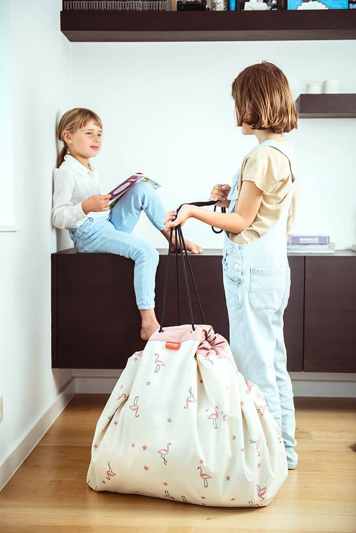 Walk in a Park toy storage bag, 2 girls talking while reading a book and carrying the bag