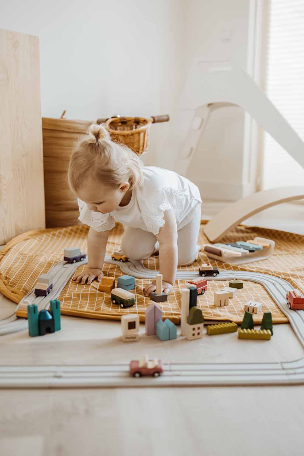 open organic grid mustard storage bag, child playing with wooden toys, kidsroom, white slide, tricycle