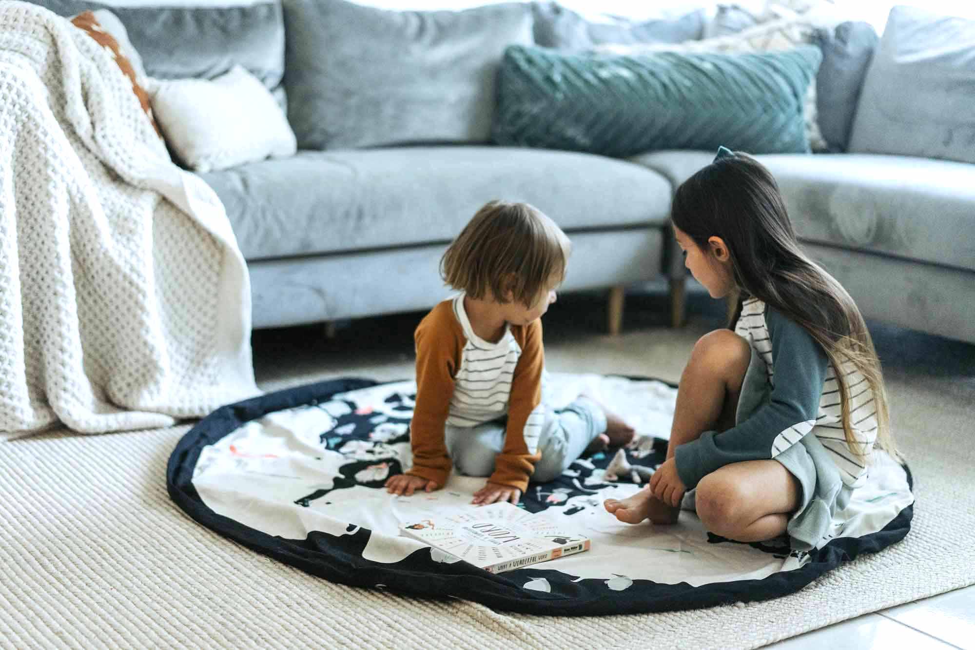 worldmap/stars storage bag, children sitting on the mat on carpet in livingroomn, next to sofa