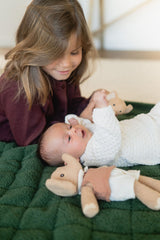 noomad soft teddy evergreen, child is looking at baby lying on open mat between cuddles