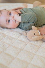 noomad soft teddy oak, baby is lying on the mat with cuddle, awake