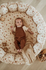 bloom rabbit babymat, crib, raised edges, baby is lying in the crib on blanket, wooden toys