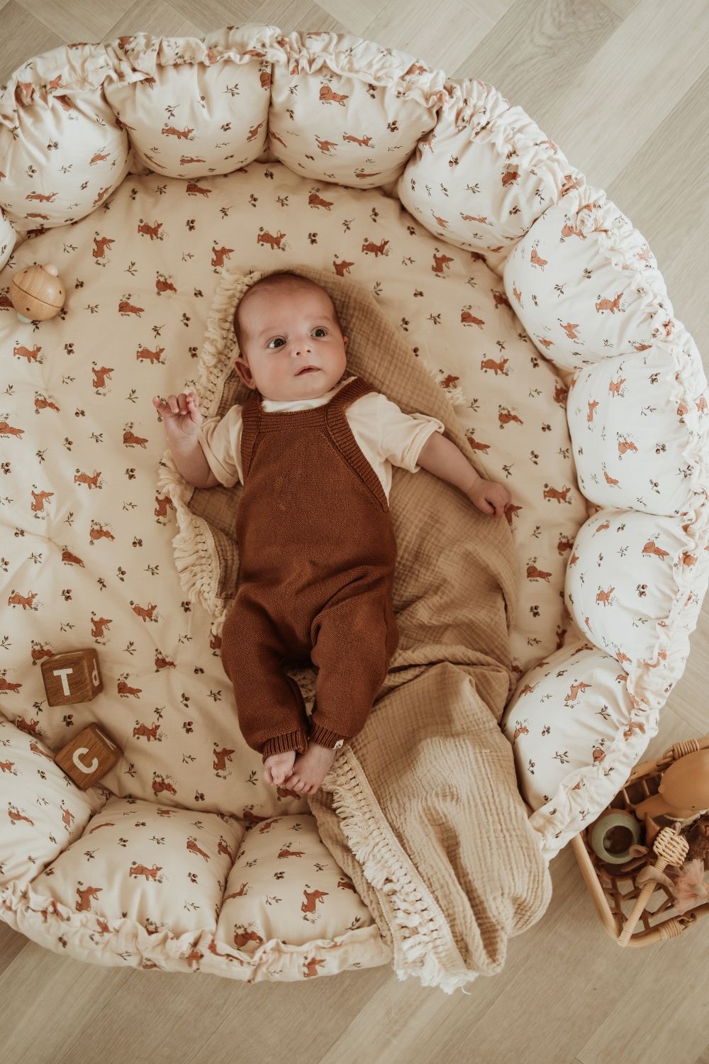bloom rabbit babymat, crib, raised edges, baby is lying in the crib on blanket, wooden toys