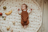 rabbit soft organic babymat, open on floor, little baby is sleeping on the mat, wooden fruit toys