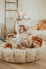 bloom rabbit babymat, crib, raised edges, filled with cuddles, child is playing in the crib with the cuddles