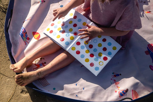 Beach outdoor storage bag, a child is reading a book on a colorful outdoor playmat