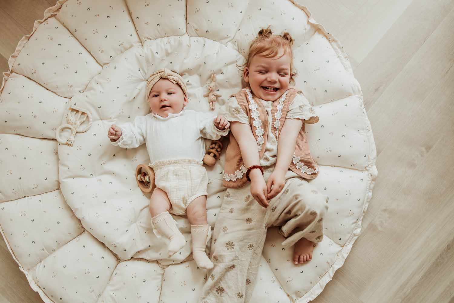 Bloom moon organic babymat, baby and todler lying on open mat, wooden toys