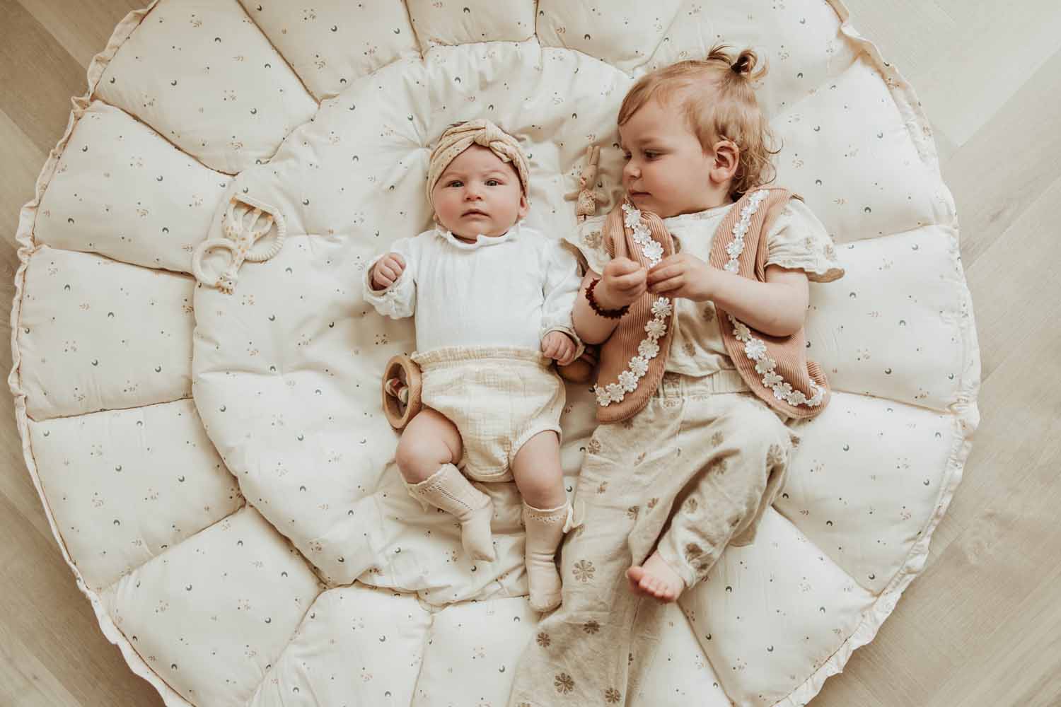 Bloom moon organic babymat, baby and todler lying on open mat, wooden toys