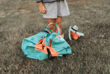 outdoor play storage bag, closed, bag in garden, next to child