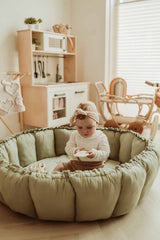 Bloom meadow green organic babymat, raised edges, baby sitting on mat in kidsroom, wooden kitchen