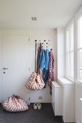 Stripes brown toy storage bag and play mat, hanging on coat rack next to jackets, stripes pink storage bag closed on floor