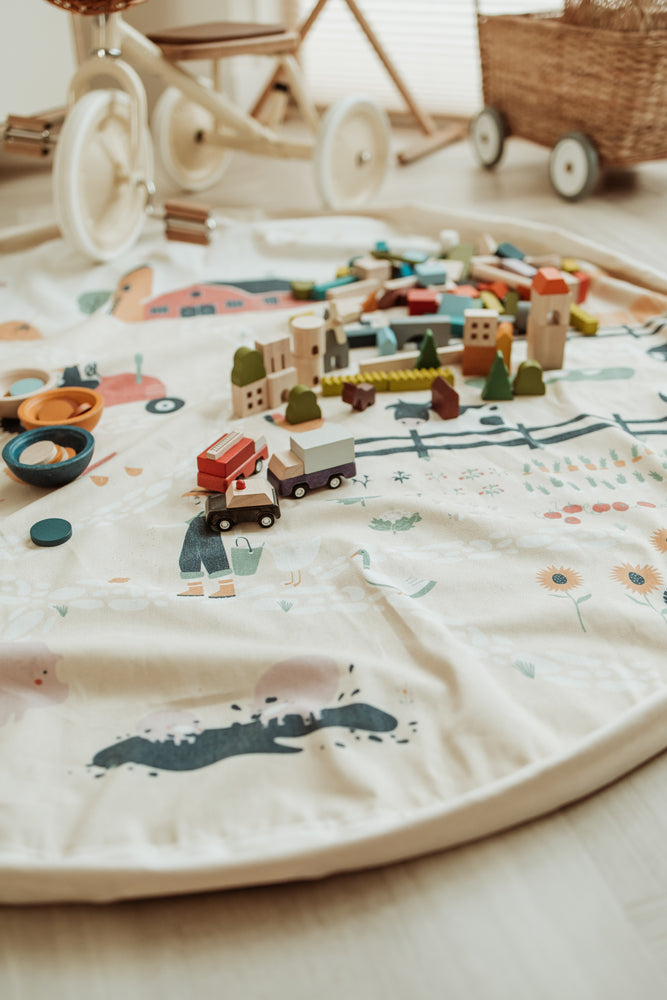 farm storage bag, open on floor in kidsroom, white tricycle, wooden toys