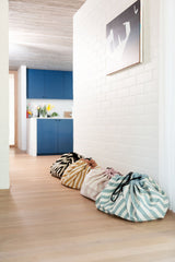 toy storage bag and play mat, cool black, mustard, pink and green stripes, different bags against white wall
