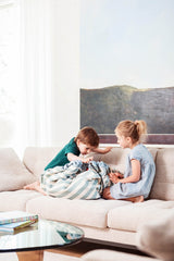 toy storage bag and play mat, kids sitting in sofa, green striped bag between the kids